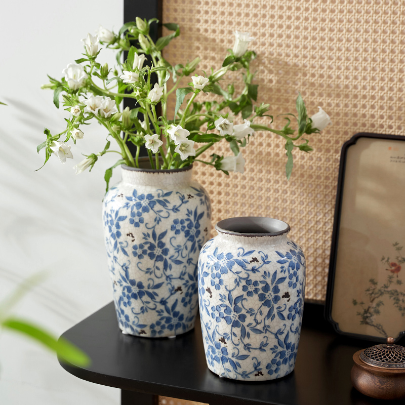 Blue and white Chinese porcelain vases with white blossoms displayed on a modern black table.