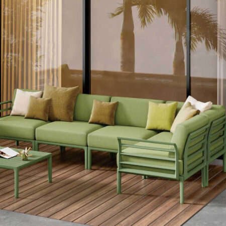 Olive green modular outdoor sofa set with aluminum frame on wooden deck, surrounded by tropical scenery