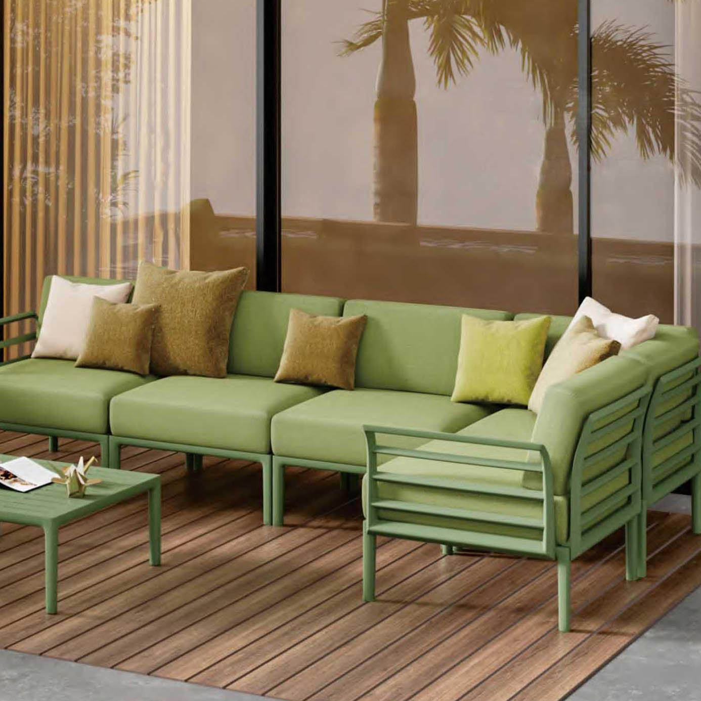 Olive green modular outdoor sofa set with aluminum frame on wooden deck, surrounded by tropical scenery