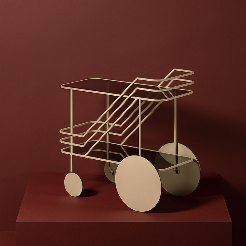 beige bar cart against a deep red wall, showcasing its sculptural lines and modern look