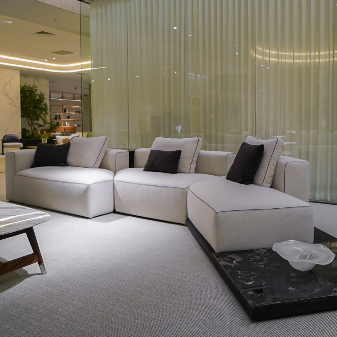Basketweave modular sofa with black piping and marble platform, displayed in a luxurious showroom setting.